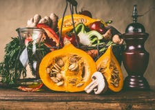 Zucca sul tavolo da cucina con il canestro degli ingredienti delle verdure al fondo rustico della parete, vista frontale fotografia stock libera da diritti Zucca sul tavolo da cucina con il canestro degli ingredienti delle verdure al fondo rustico della parete, vista frontale fotografia stock libera da diritti
