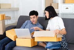Zufälliger arbeitender Kleinbetrieb der jungen asiatischen Paare, der online sie ein Notizbuch verwendend verpackt Schauen auf ei stockbild Zufälliger arbeitender Kleinbetrieb der jungen asiatischen Paare, der online sie ein Notizbuch verwendend verpackt Schauen auf ei stockbild