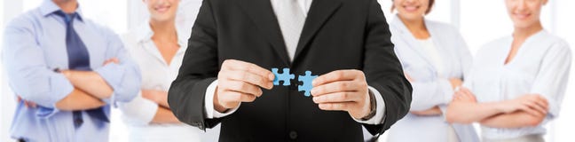 Zusammenpassende Puzzlespielstücke des Mannes über Geschäftsteam lizenzfreies stockbild Zusammenpassende Puzzlespielstücke des Mannes über Geschäftsteam lizenzfreies stockbild