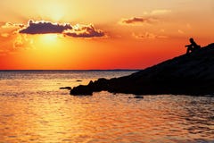 Zwart silhouet van jonge mensenzitting op zonsondergang overzees strand stock fotografie Zwart silhouet van jonge mensenzitting op zonsondergang overzees strand stock fotografie