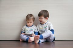 Zwei Brüder in den gleichen Pyjamas spielen Spiele im Gerät stockfoto Zwei Brüder in den gleichen Pyjamas spielen Spiele im Gerät stockfoto