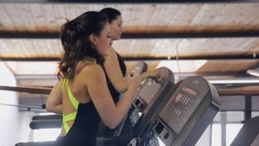 Zwei Frauen Brunette, der auf einem Tretmühlensimulator lächelt und läuft Zwei Frauen Brunette, der auf einem Tretmühlensimulator lächelt und läuft