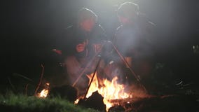 Zwei Freunde sitzt nahe bei Feuer im Holz nachts und spricht und trinkt Tee stock video footage Zwei Freunde sitzt nahe bei Feuer im Holz nachts und spricht und trinkt Tee stock video footage