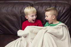 Zwei glückliche Jungen, die auf einer Couch zusammen fernsieht sitzen lizenzfreies stockfoto Zwei glückliche Jungen, die auf einer Couch zusammen fernsieht sitzen lizenzfreies stockfoto
