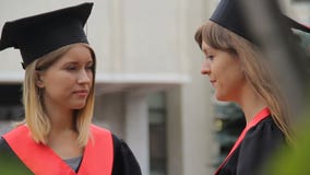 Zwei hübsche Studenten, die im Park nach Graduierungsfeier, glückliche Zukunft sprechen stock footage Zwei hübsche Studenten, die im Park nach Graduierungsfeier, glückliche Zukunft sprechen stock footage