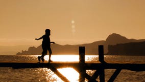 Zwei Kinder, die auf Brücke bei Sonnenuntergang laufen stock footage Zwei Kinder, die auf Brücke bei Sonnenuntergang laufen stock footage