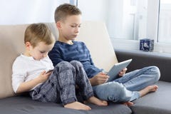 Zwei Kinder unter Verwendung Tablette PC und smartphon zu Hause Brüder mit Tablet-Computer im hellen Raum Jungen, die Spiele auf lizenzfreie stockfotos Zwei Kinder unter Verwendung Tablette PC und smartphon zu Hause Brüder mit Tablet-Computer im hellen Raum Jungen, die Spiele auf lizenzfreie stockfotos