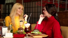 Zwei l?chelnde M?dchen Cocktails trinken und Burger in einem hellen Restaurant essen stock footage Zwei l?chelnde M?dchen Cocktails trinken und Burger in einem hellen Restaurant essen stock footage