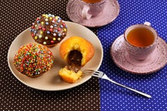 Zwei Tassen Tee mit kleinen Kuchen und Schokolade mit einem mehrfarbigen Pulver auf dem Tisch stockbild Zwei Tassen Tee mit kleinen Kuchen und Schokolade mit einem mehrfarbigen Pulver auf dem Tisch stockbild