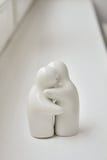 Zwei weiße keramische Figürchen für Salz und Pfeffer in einer menschlichen Form werden auf einer weißen Oberfläche umarmt lizenzfreie stockfotografie Zwei weiße keramische Figürchen für Salz und Pfeffer in einer menschlichen Form werden auf einer weißen Oberfläche umarmt lizenzfreie stockfotografie