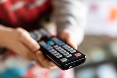 À télécommande de TV tenu dans le women& x27 ; mains de s Canaux de commutation sur t images stock À télécommande de TV tenu dans le women& x27 ; mains de s Canaux de commutation sur t images stock