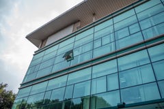 Ángulo bajo del edificio de oficinas con el exterior de cristal en fondo del cielo de las nubes imagenes de archivo Ángulo bajo del edificio de oficinas con el exterior de cristal en fondo del cielo de las nubes imagenes de archivo