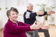 Ältere Frau, die glücklich mit ihrem Freund während der pilates für Senioren trainiert lizenzfreies stockbild Ältere Frau, die glücklich mit ihrem Freund während der pilates für Senioren trainiert lizenzfreies stockbild