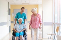 Ältere Frau im Rollstuhl mit Krankenschwester im Krankenhaus stockbild Ältere Frau im Rollstuhl mit Krankenschwester im Krankenhaus stockbild