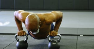 Älterer Mann, der Liegestütz mit kettlebell im Eignungsstudio 4k tut stock footage Älterer Mann, der Liegestütz mit kettlebell im Eignungsstudio 4k tut stock footage