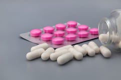 Åstadkomma blåsor på med röda preventivpillerar och vita preventivpillerar spridda från kruset på en grå bakgrund royaltyfri foto Åstadkomma blåsor på med röda preventivpillerar och vita preventivpillerar spridda från kruset på en grå bakgrund royaltyfri foto