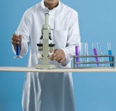 Écolier à l'aide d'un microscope avec des produits chimiques dans des tubes à essai photographie stock Écolier à l'aide d'un microscope avec des produits chimiques dans des tubes à essai photographie stock