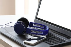 Écouteurs bleus et un repos futé de téléphone sur un ordinateur portable avec le chemin de coupure sur l'espace d'écran et de cop photographie stock Écouteurs bleus et un repos futé de téléphone sur un ordinateur portable avec le chemin de coupure sur l'espace d'écran et de cop photographie stock