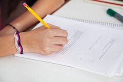 Écriture d'écolière sur le papier au bureau photographie stock libre de droits Écriture d'écolière sur le papier au bureau photographie stock libre de droits
