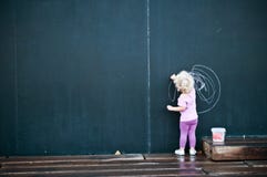 Écriture de petite fille sur le grand tableau noir photo libre de droits Écriture de petite fille sur le grand tableau noir photo libre de droits