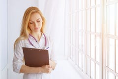 Écriture de stylo de participation de docteur de femme sur le presse-papiers pour prendre le patient image stock Écriture de stylo de participation de docteur de femme sur le presse-papiers pour prendre le patient image stock