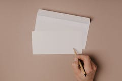 Écrivant une lettre à la main sur le fond beige image libre de droits Écrivant une lettre à la main sur le fond beige image libre de droits