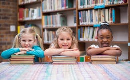Élèves mignons souriant à l'appareil-photo dans la bibliothèque photo stock Élèves mignons souriant à l'appareil-photo dans la bibliothèque photo stock