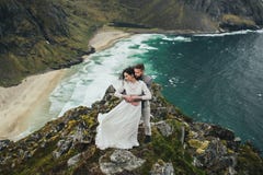 Épouser des voyageurs de couples sur une colline en Norvège, Kvalvika Belle vue de la plage, Lofoten, Norvège photo stock Épouser des voyageurs de couples sur une colline en Norvège, Kvalvika Belle vue de la plage, Lofoten, Norvège photo stock