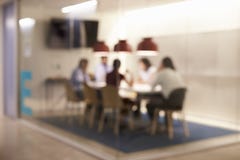 Équipe d'entreprise constituée en société à la table dans un compartiment de lieu de réunion, defocussed image libre de droits Équipe d'entreprise constituée en société à la table dans un compartiment de lieu de réunion, defocussed image libre de droits