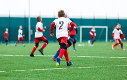 Équipes de football - garçons dans le football uniforme rouge, bleu, blanc de jeu sur le champ vert garçons ruisselant qualificat photographie stock Équipes de football - garçons dans le football uniforme rouge, bleu, blanc de jeu sur le champ vert garçons ruisselant qualificat photographie stock