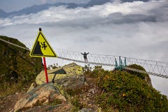 Équipez la marche sur le pont suspendu et regarder les montagnes nuageuses ci-dessous photo libre de droits Équipez la marche sur le pont suspendu et regarder les montagnes nuageuses ci-dessous photo libre de droits