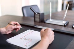 Équipez se reposer au stylo de table et de prises dans sa main Il y a feuille de papier avec un diagramme marchand sur la table P photo libre de droits Équipez se reposer au stylo de table et de prises dans sa main Il y a feuille de papier avec un diagramme marchand sur la table P photo libre de droits