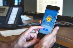 Équipez tenir un téléphone intelligent mobile avec une application de protection des données montrant un cadenas jaune images stock Équipez tenir un téléphone intelligent mobile avec une application de protection des données montrant un cadenas jaune images stock