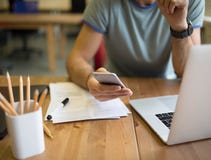 Étroitement type de hippie causant dans l'Internet par l'intermédiaire du téléphone de cellules, se reposant au bureau images stock Étroitement type de hippie causant dans l'Internet par l'intermédiaire du téléphone de cellules, se reposant au bureau images stock