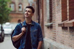 Étudiant avec le sac à dos en denim, promenades sur la rue photo stock Étudiant avec le sac à dos en denim, promenades sur la rue photo stock
