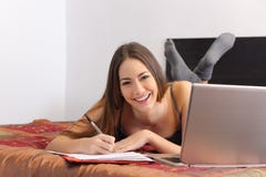 Étudiant heureux étudiant avec un ordinateur portable dans sa chambre à coucher images stock Étudiant heureux étudiant avec un ordinateur portable dans sa chambre à coucher images stock