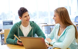 Étudiants heureux avec l'ordinateur portable et les livres à la bibliothèque photo stock Étudiants heureux avec l'ordinateur portable et les livres à la bibliothèque photo stock