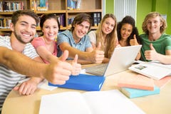 Étudiants universitaires faisant des gestes des pouces dans la bibliothèque image stock Étudiants universitaires faisant des gestes des pouces dans la bibliothèque image stock