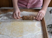 Δίνει την κυλώντας ζύμη με μια κυλώντας καρφίτσα αποτύπωσης σε ανάγλυφο, σε ένα ξύλινο υπόβαθρο στοκ εικόνα με δικαίωμα ελεύθερης χρήσης Δίνει την κυλώντας ζύμη με μια κυλώντας καρφίτσα αποτύπωσης σε ανάγλυφο, σε ένα ξύλινο υπόβαθρο στοκ εικόνα με δικαίωμα ελεύθερης χρήσης