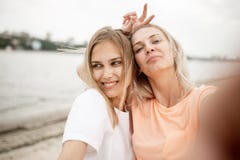 Δύο νέα ελκυστικά ξανθά κορίτσια παίρνουν ένα selfie στην παραλία μια θερμή θυελλώδη ημέρα στοκ φωτογραφία με δικαίωμα ελεύθερης χρήσης Δύο νέα ελκυστικά ξανθά κορίτσια παίρνουν ένα selfie στην παραλία μια θερμή θυελλώδη ημέρα στοκ φωτογραφία με δικαίωμα ελεύθερης χρήσης