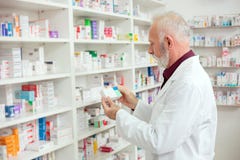 Ανώτερος αρσενικός φαρμακοποιός που φθάνει για τα φάρμακα από το ράφι στοκ φωτογραφία με δικαίωμα ελεύθερης χρήσης Ανώτερος αρσενικός φαρμακοποιός που φθάνει για τα φάρμακα από το ράφι στοκ φωτογραφία με δικαίωμα ελεύθερης χρήσης