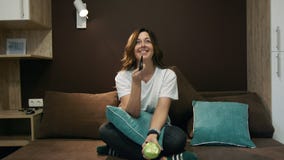 Γυναίκα που προσέχει τη TV και που τρώει τη Apple που κάθεται στο κρεβάτι στην κρεβατοκάμαρα Κανάλια διακοπτών με τον τηλεχειρισμ απόθεμα βίντεο Γυναίκα που προσέχει τη TV και που τρώει τη Apple που κάθεται στο κρεβάτι στην κρεβατοκάμαρα Κανάλια διακοπτών με τον τηλεχειρισμ απόθεμα βίντεο