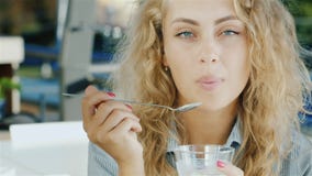 Ελκυστική νέα γυναίκα που τρώει το παγωτό στον καφέ, που χαμογελά στη κάμερα απόθεμα βίντεο Ελκυστική νέα γυναίκα που τρώει το παγωτό στον καφέ, που χαμογελά στη κάμερα απόθεμα βίντεο