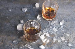 Εορτασμός στο φραγμό Ζευγάρι των γυαλιών με το ουίσκυ και κομμάτια του πάγου στον γκρίζο πίνακα στοκ φωτογραφίες Εορτασμός στο φραγμό Ζευγάρι των γυαλιών με το ουίσκυ και κομμάτια του πάγου στον γκρίζο πίνακα στοκ φωτογραφίες
