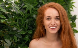 Εύθυμη redhead γυναίκα που γελά μέσω των φύλλων monstera στοκ φωτογραφία με δικαίωμα ελεύθερης χρήσης Εύθυμη redhead γυναίκα που γελά μέσω των φύλλων monstera στοκ φωτογραφία με δικαίωμα ελεύθερης χρήσης