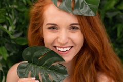 Εύθυμη redhead γυναίκα που γελά μέσω των φύλλων monstera στοκ εικόνες με δικαίωμα ελεύθερης χρήσης Εύθυμη redhead γυναίκα που γελά μέσω των φύλλων monstera στοκ εικόνες με δικαίωμα ελεύθερης χρήσης