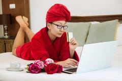 Εύθυμη γυναίκα που ψωνίζει on-line με την πιστωτική κάρτα και το φορητό προσωπικό υπολογιστή σε ένα κρεβάτι στοκ φωτογραφίες Εύθυμη γυναίκα που ψωνίζει on-line με την πιστωτική κάρτα και το φορητό προσωπικό υπολογιστή σε ένα κρεβάτι στοκ φωτογραφίες
