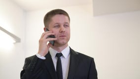 Εύθυμος επιχειρηματίας πορτρέτου που χαμογελά και που μιλά με κινητό τηλέφωνο στην αρχή φιλμ μικρού μήκους Εύθυμος επιχειρηματίας πορτρέτου που χαμογελά και που μιλά με κινητό τηλέφωνο στην αρχή φιλμ μικρού μήκους