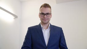 Επιτυχές επιχειρησιακό άτομο eyeglasses και το μπλε κοστούμι που φαίνεται ρολόι καρπών στην αρχή απόθεμα βίντεο Επιτυχές επιχειρησιακό άτομο eyeglasses και το μπλε κοστούμι που φαίνεται ρολόι καρπών στην αρχή απόθεμα βίντεο