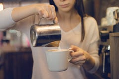 Επιχειρησιακή έννοια καφέ - γυναικείο barista κινηματογραφήσεων σε πρώτο πλάνο στο προετοιμαζόμενο και χύνοντας γάλα ποδιών στοκ εικόνα Επιχειρησιακή έννοια καφέ - γυναικείο barista κινηματογραφήσεων σε πρώτο πλάνο στο προετοιμαζόμενο και χύνοντας γάλα ποδιών στοκ εικόνα